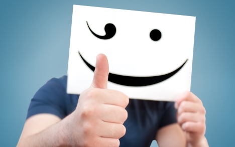 Suboxone addict hiding face behind a paper with smiley face.