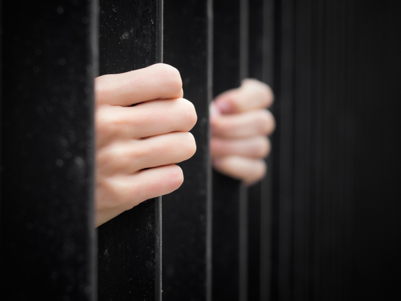 womans hands prison bars