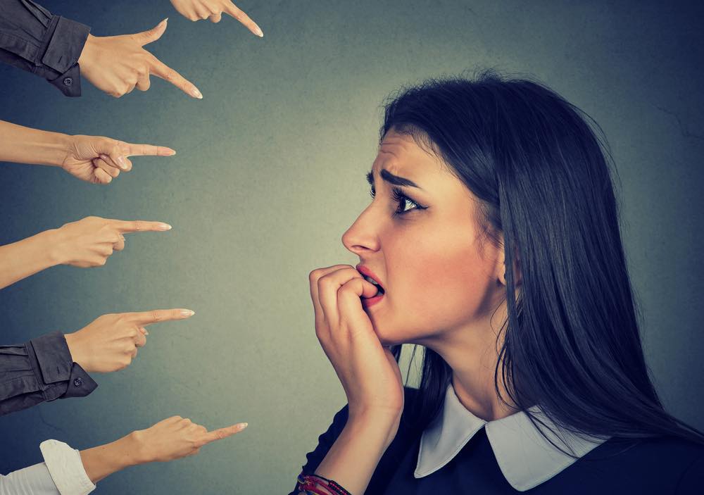 Is Guilt Selfish? A woman's face with several hands pointing fingers at her.