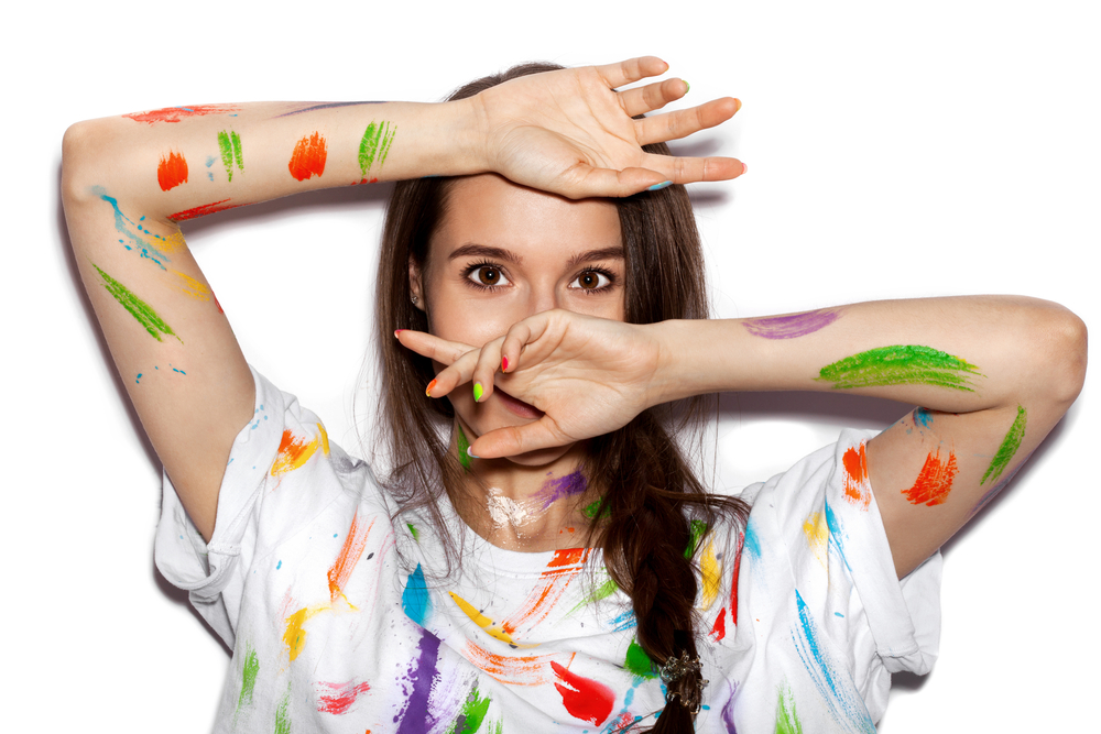 A woman with paint all over her shirt and arms.