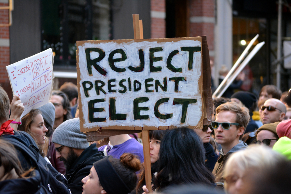 People holding a sign saying "Reject President Elect"