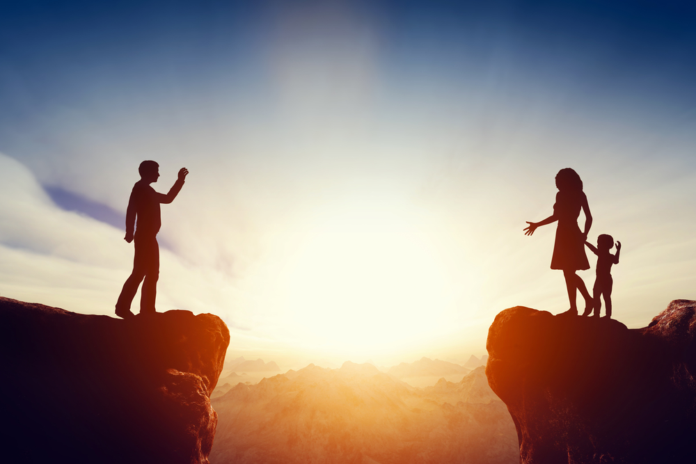 Silhouettes of man separated from woman and child by big chasm