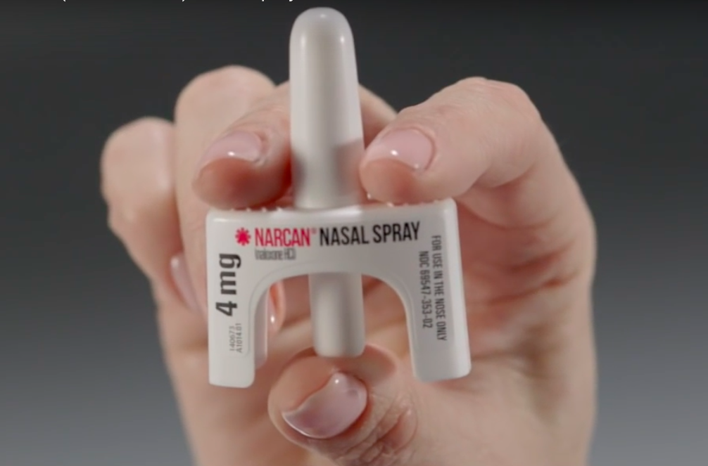 A hand holding Narcan nasal spray.