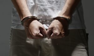 Hands balled into fists, in handcuffs.