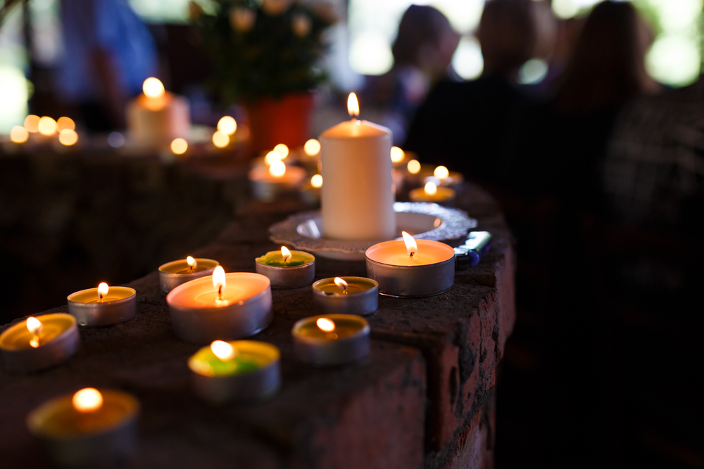 An arrangement of candles in the foreground of a funeral.
