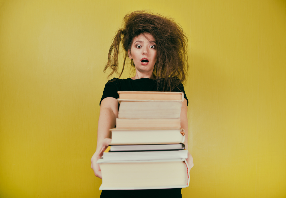 A frazzled woman holding a stack of books.