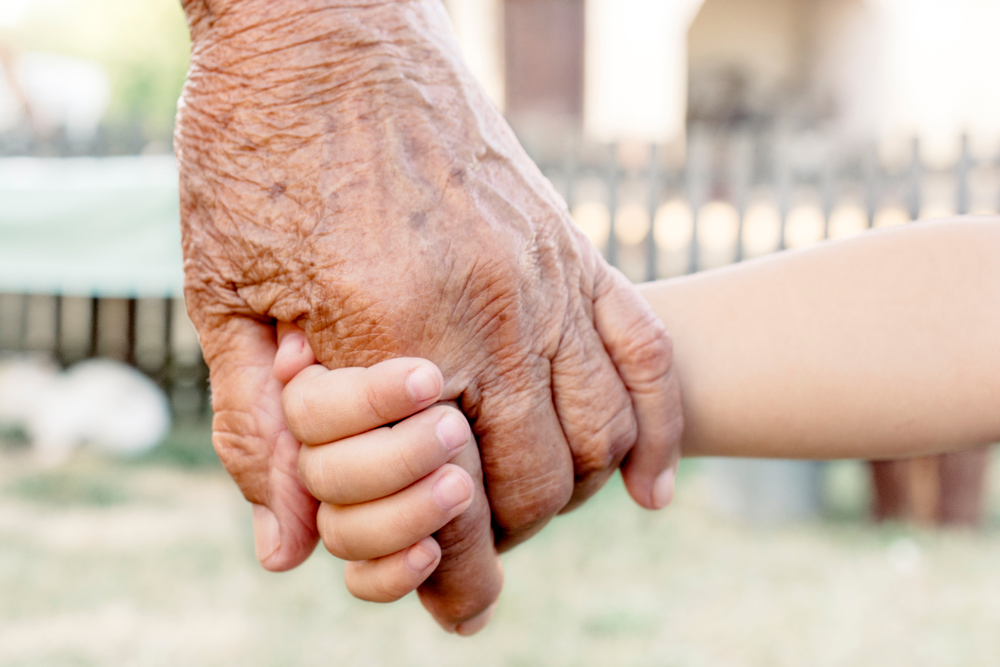 An older hand holding a child's hand.