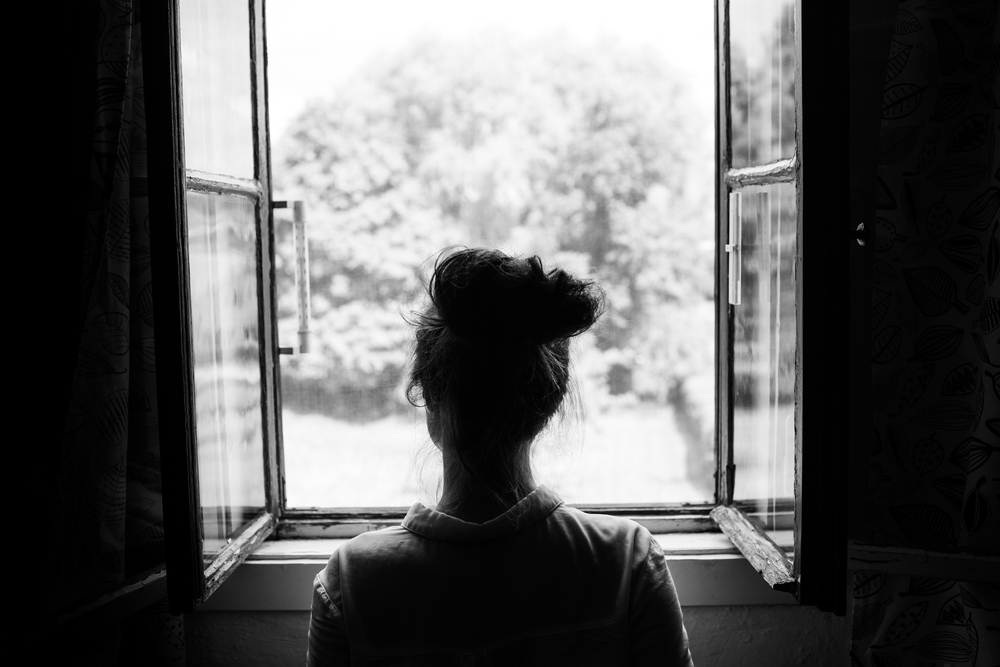 Woman looking pensively out window.