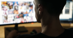 A darkened silhouette of a man's head looking at a screen full of blurry images.