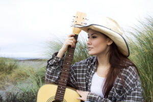 Woman in cowboy hat with guitar.