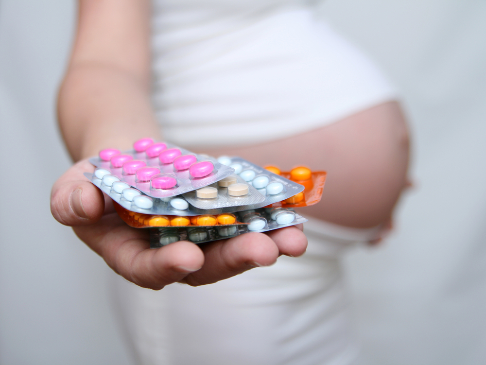 Pregnant woman holding pills.