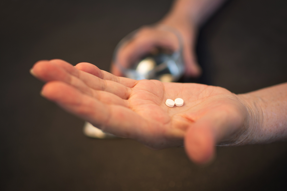 Person displaying 2 pills in the palm of their hand.