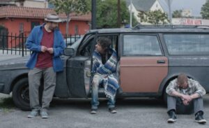 Three heroin addicts next to a car