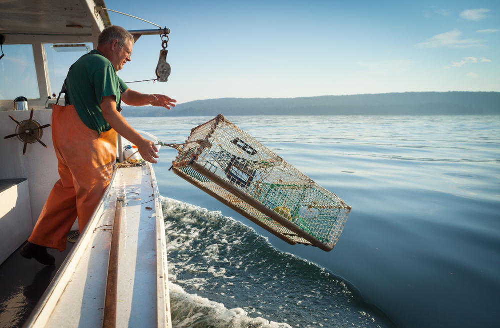 A lobsterman throwing a lobster trap into the ocean.