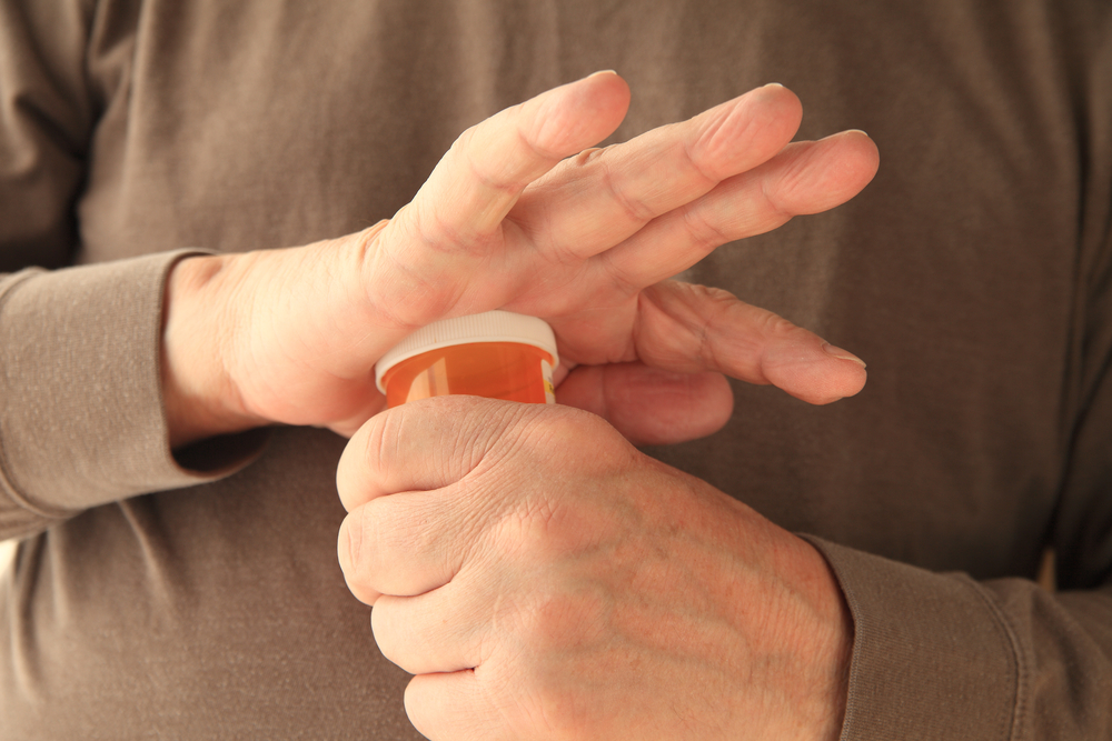 Man attempting to open child-proof prescription pill bottle.