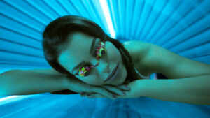 woman in protective goggles laying inside a tanning bed.
