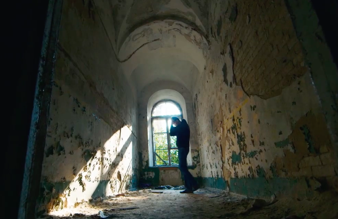 Man dressed in black pacing inside isolated room while battling effects of anxiety.