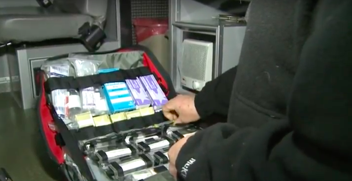 a paramedic taking narcan out of his emergency medical kit.