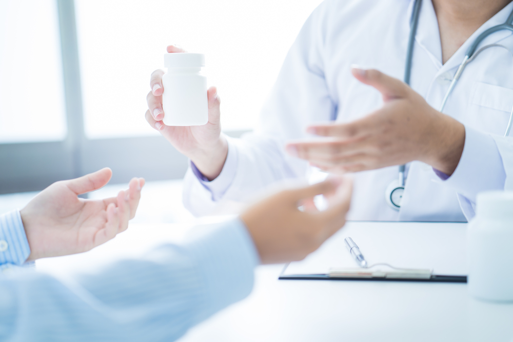 A doctor handing a bottle of pills to a patient.