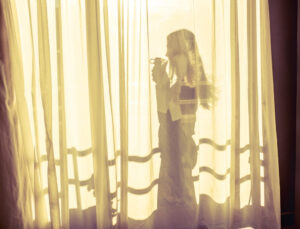 The silhouette of a woman behind a curtain.