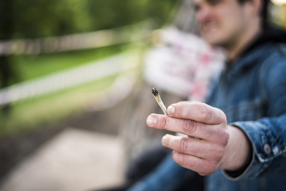 Man holding a small marijuana joint in his hand.