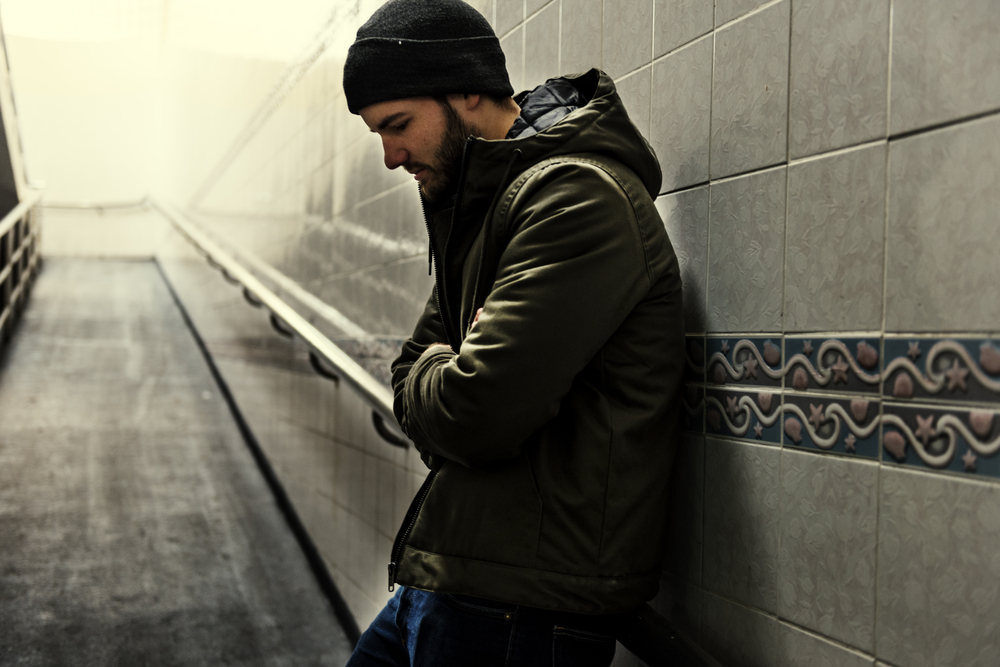 Man leaning on wall looking down