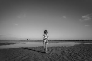Woman looking off, grieving, at shallow water bed