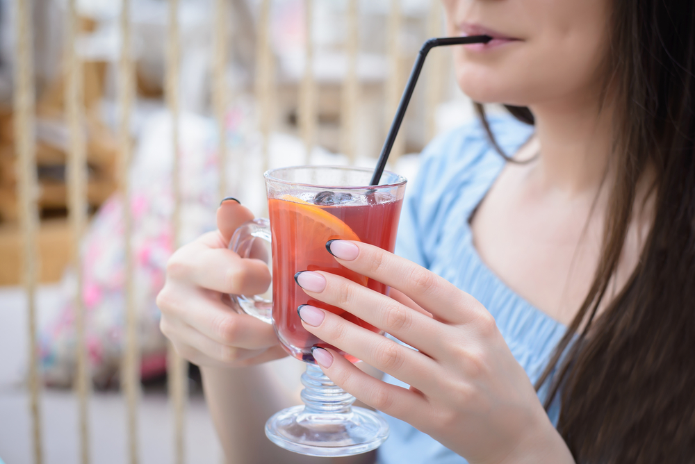 Woman drinking cocktail drink from straw.