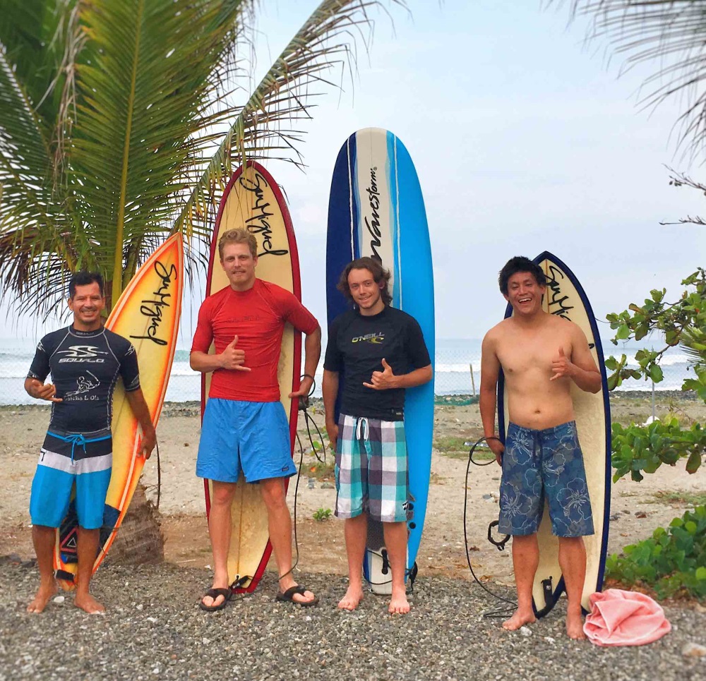 4 men standing in front of surf boards