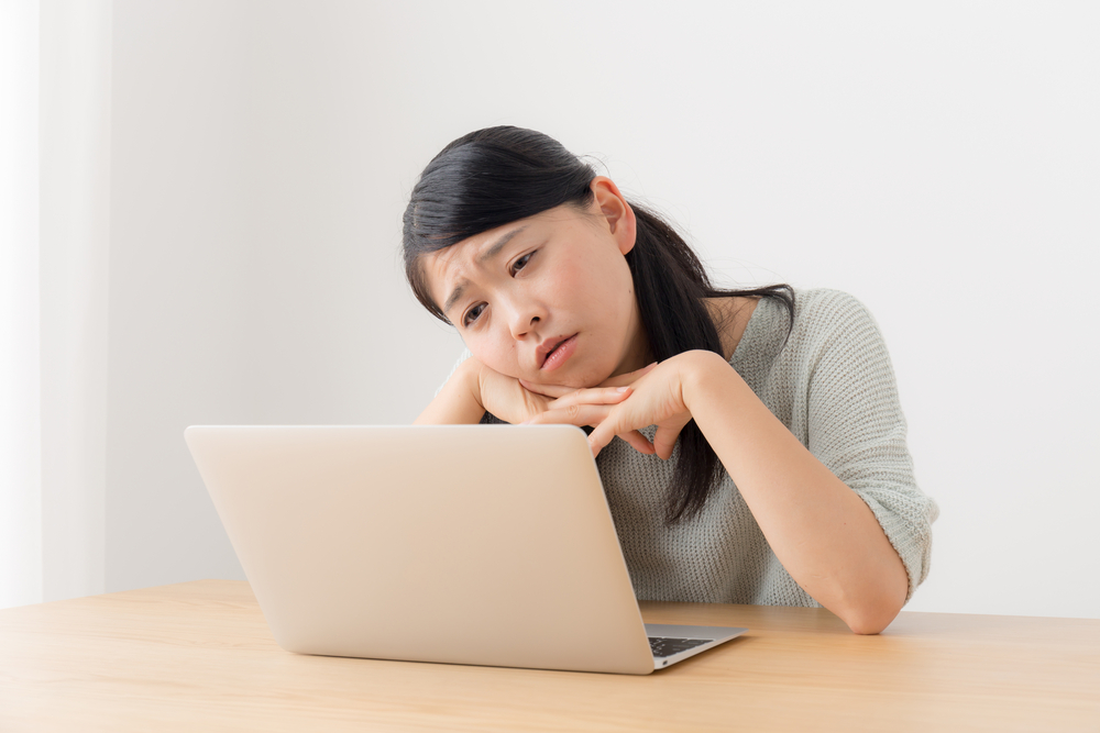 Sad woman looking at a laptop screen.