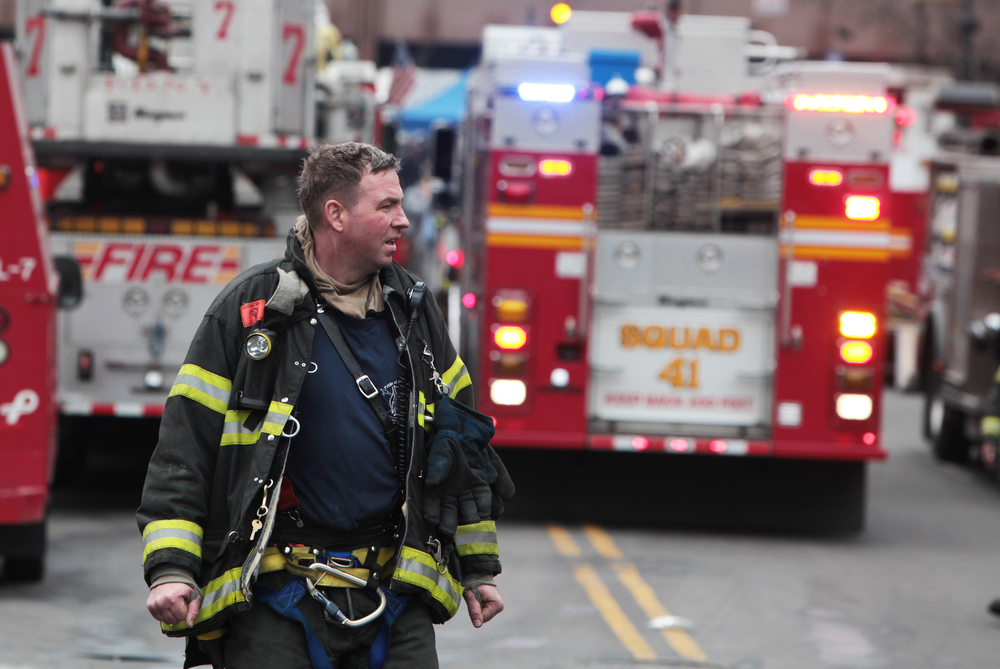 a fireman standing in front of two firetrucks.