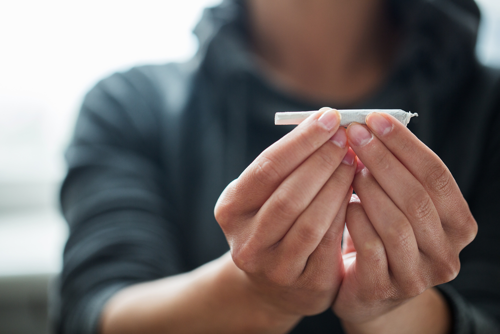 Women holding out a marijuana joint in her hands.