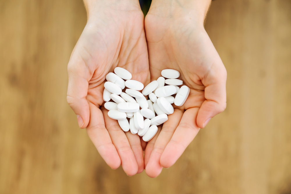 hands holding a pile of white pills
