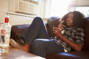 Woman smoking cigarette and watching television with vodka on table
