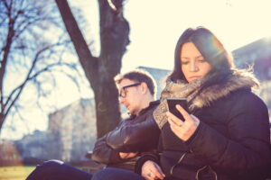 Serious woman sitting in park next to man