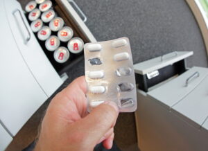 hand holding pills with cans in background