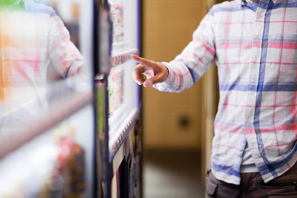 A man standing in front of a vending machine about to make a selection.