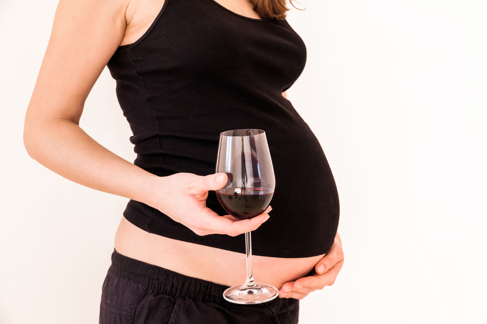 pregnant woman holding a glass of red wine.