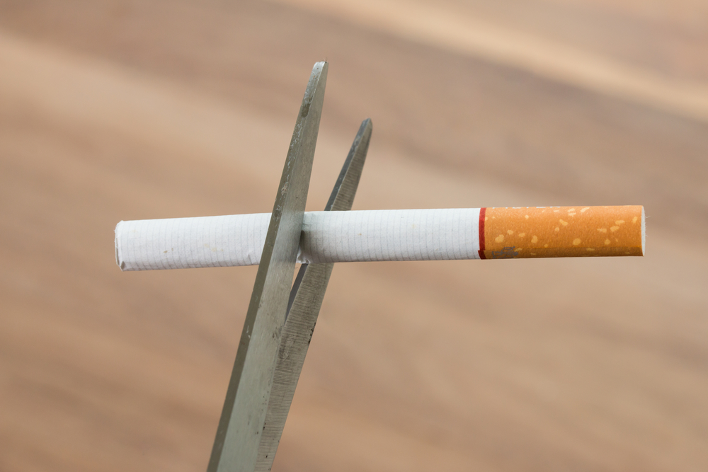 Cigarette being cut in half by a pair of scissors.