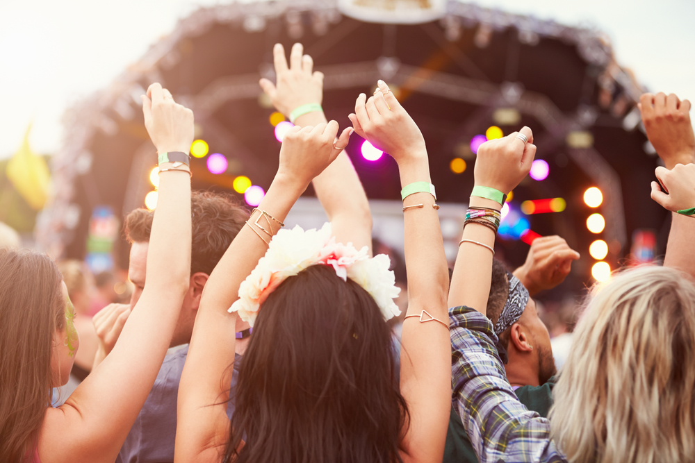 people waving their hands in the air at an outdoor music festival
