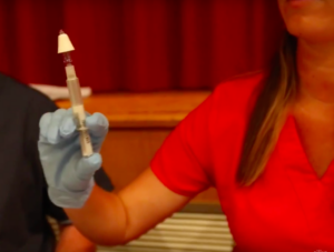 person holding a syringe filled with naloxone.