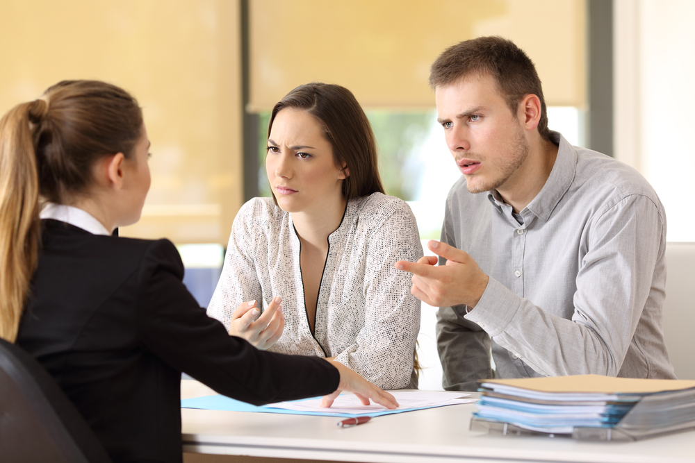 Angry couple claiming to a businesswoman at office