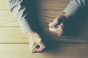 man clenching fists on wooden table