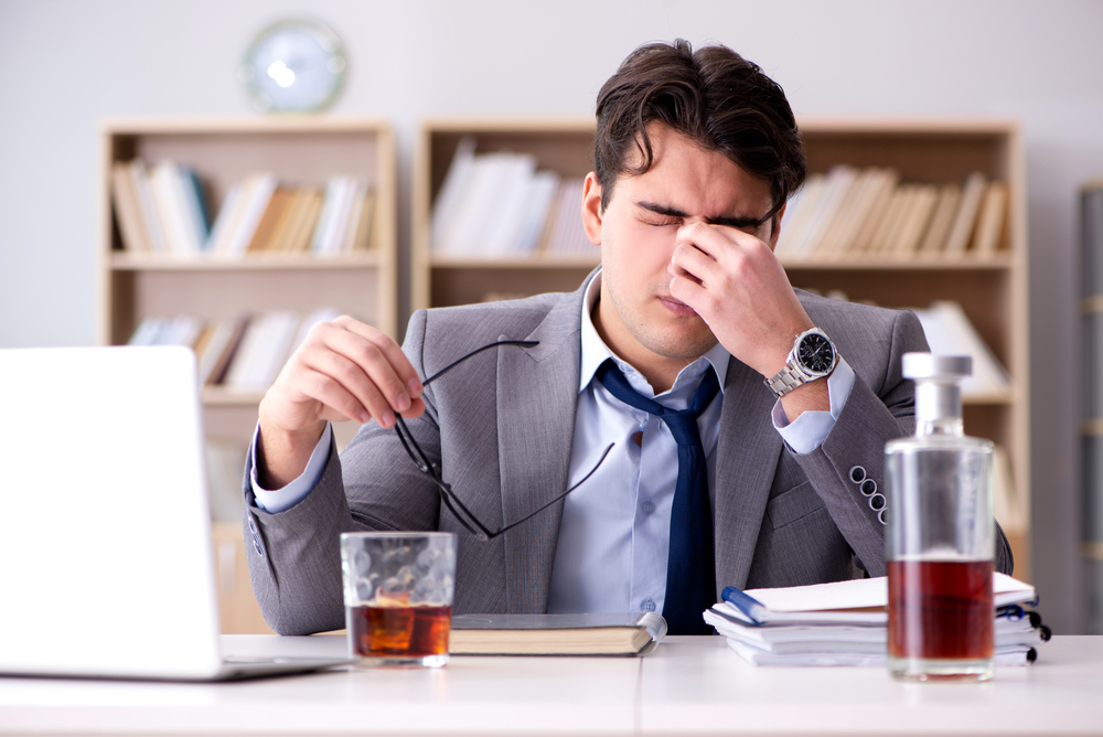 stressed businessman drinking alcohol in the office