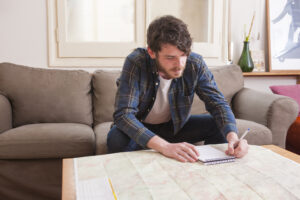 young man sitting at table writing in notebook
