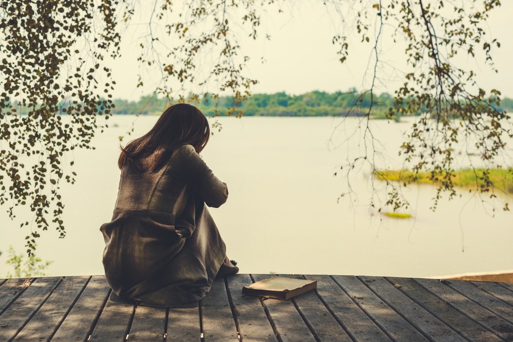 woman sitting alone by the water