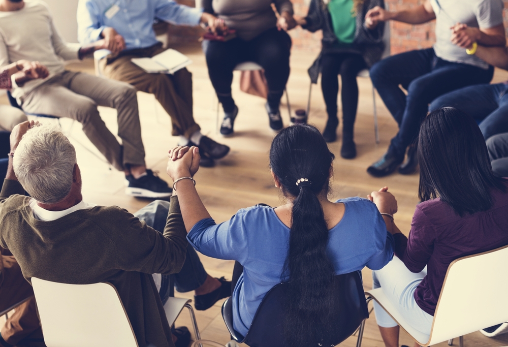 a group of people holding hands while sitting in a circle