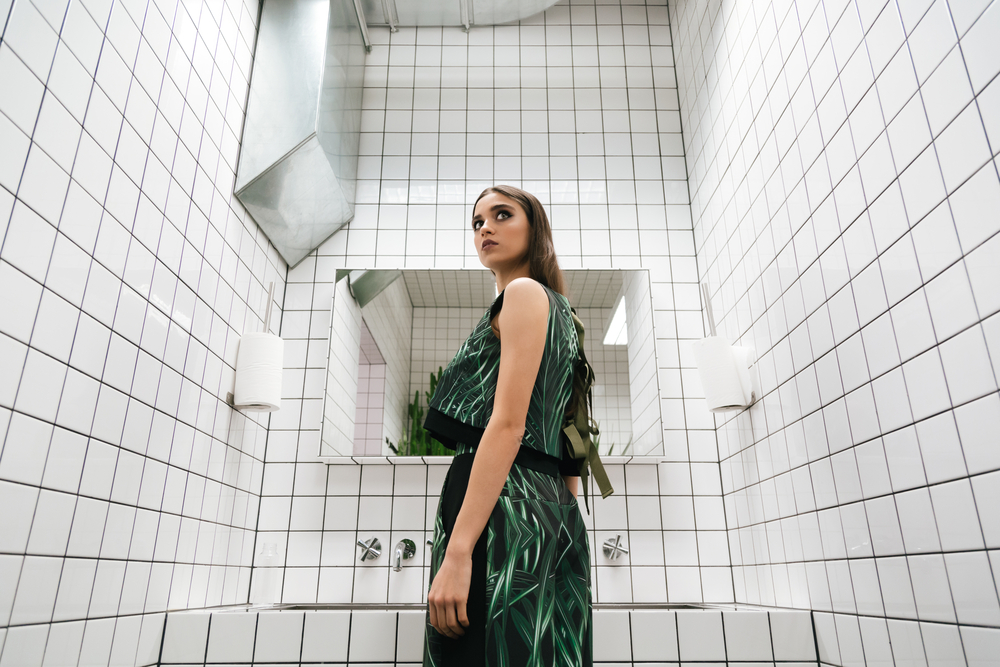 A woman in a restroom, looking behind her.