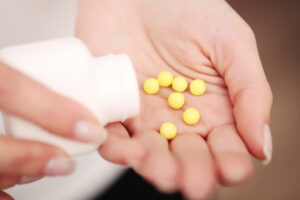 close up of woman's hand holding yellow pills.