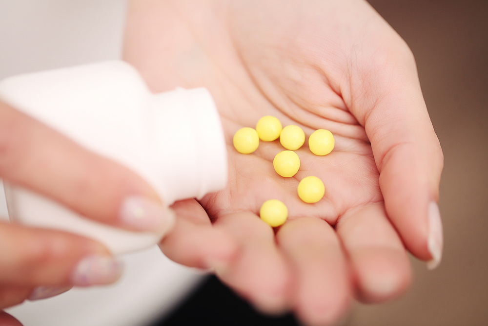 close up of woman's hand holding yellow pills.